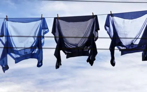 Drei blaue Hemden trocknen auf der Wäscheleine. Sie wurden auf links gewaschen, um die Farben zu schonen.