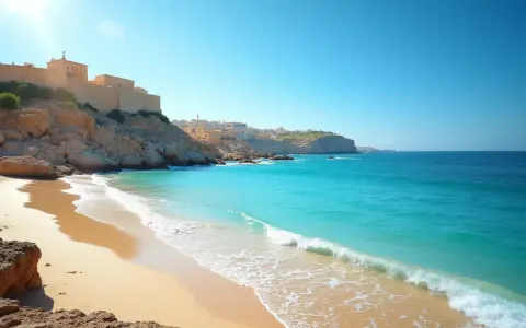 Piękna plaża z turkusową wodą i klifami, na których widać zabudowania. Czy to Cypr czy Malta? Trudno odróżnić te rajskie widoki.