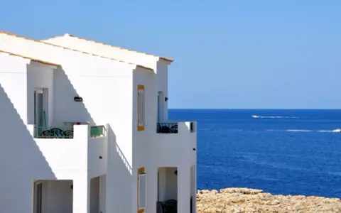 Maison blanche avec balcons face à la mer bleue. Idéal pour un dédommagement location saisonnière.