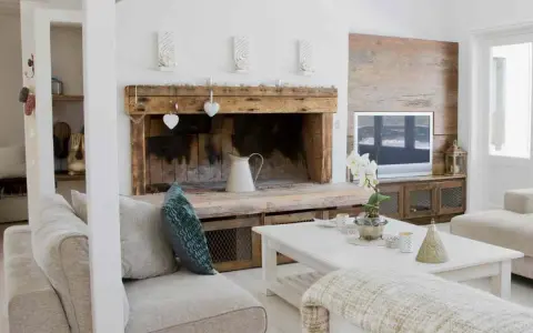 Un camino rustico con decorazioni a cuore e una brocca bianca, un'idea per come decorare un camino in stile country.