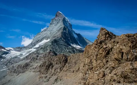 Majestatyczny Matterhorn wznosi się na tle błękitnego nieba. Widok zapiera dech w piersiach, sugerując trudne wejście na Matterhorn.