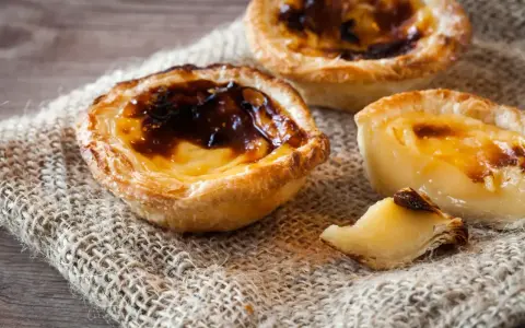 Tre krämiga portugisiska bakelser med karamelliserad yta, en klassiker inom portugisisk mat.