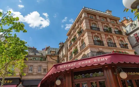 Bistrot Chez Rémy, ein Ratatouille Restaurant in Paris, mit typisch französischen Gebäuden und einem roten Vordach.