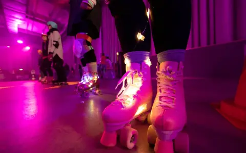 Rollschuh-Spaß auf der Zollverein Rollschuhbahn im Neonlicht. Bunte Lichter schmücken die Rollschuhe, während die Skater über den Boden gleiten.