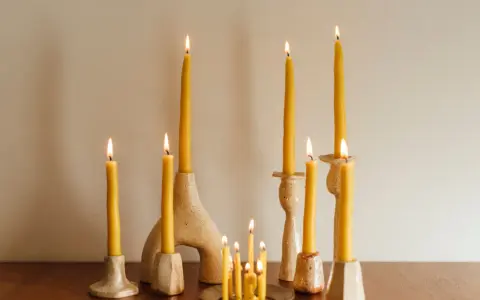 Velas amarillas de abeja en candelabros de cerámica. Una vela de palo santo para que sirve, ilumina el espacio con su suave resplandor.