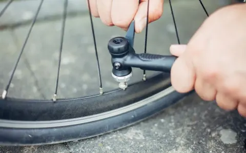 Hände pumpen mit einer Handpumpe Luft in ein Fahrradventil.