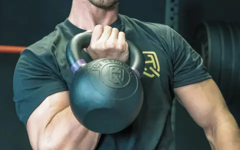 Mann hält Kettlebell, bereit für einen Kettlebell Workout Plan.