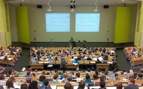 Wykład na uczelni w Szczecinie. Studenci słuchają wykładowcy na tle tablic z równaniami matematycznymi.