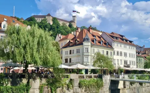 Urokliwy widok na rzekę i zabytkowe kamienice w Słowenii, Lublana. W tle widać zamek na wzgórzu.