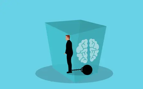 Mann in schwarzem Anzug mit Fußfessel, gefangen in einer Box mit Gehirn. Depression macht soziale Kontakte anstrengend.