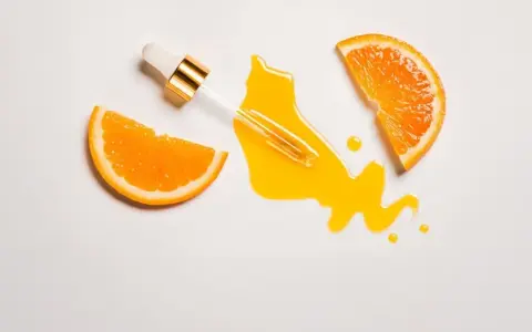 Orangenscheiben und ein Pipetten-Serum auf weißem Hintergrund. Vorsicht bei zu viel Vitamin C für die Haut, es kann Reizungen verursachen.