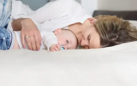 Mama tuli tuląca dziecko, ucząc się jak odkładać dziecko do łóżeczka, by spało spokojnie.