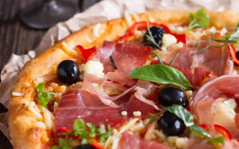 Pyszna pizza z cienko pokrojoną, aromatyczną szynką, czarnymi oliwkami i papryką. Idealna na każdą okazję!