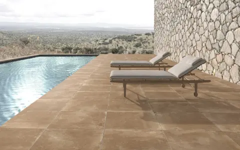 Elegante suelo para piscinas de tonos tierra, con tumbonas y vistas a un paisaje natural.