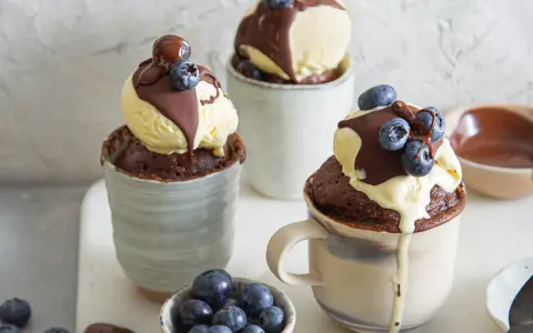Schokoladiger Tassenkuchen mit Vanilleeis, Schokosauce und Blaubeeren. Ein schnelles Tassenkuchen Rezept für süße Momente.