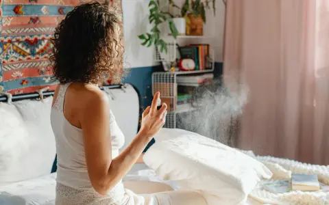 Mujer rocía almohada con spray para eliminar el olor fétido en una habitación.