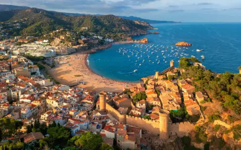 Widok na średniowieczne miasteczko z zamkiem i zatokę pełną łodzi. To idealne miejsce na odkrywanie atrakcji Costa Brava.