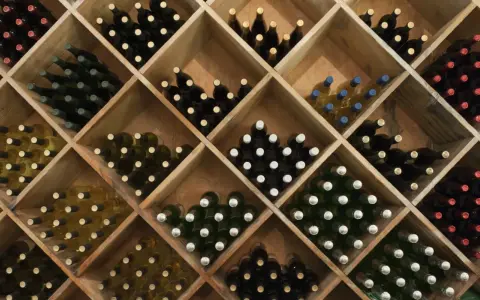 Weinregal mit vielen Flaschen Wein. Die Frage, wie lange kann man Wein lagern, hängt von der Sorte ab.