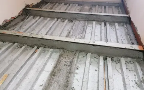 Prace nad tym, jak wzmocnić strop w starym domu. Widoczne belki stropowe i betonowanie.