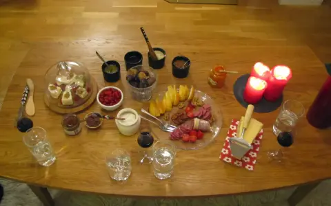 En härlig ostbricka jul med godsaker som frukt, nötter, korv och marmelad. Tre röda ljus lyser upp bordet.