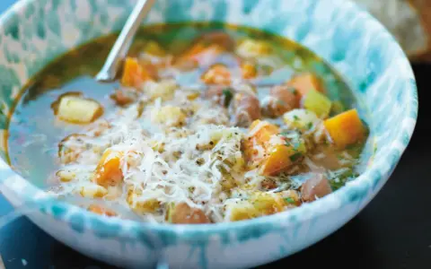 En närbild av en skål med mustig rotfruktssoppa, toppad med riven ost. Ett perfekt soppa recept för kalla dagar.