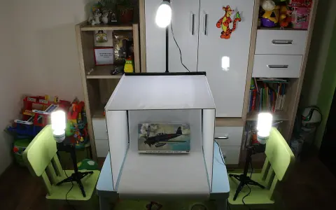 Domowy namiot bezcieniowy diy oświetla model samolotu. W tle regały z zabawkami i książkami.