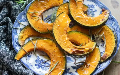 Fette di zucca in friggitrice ad aria, dorate e profumate al rosmarino, servite su un piatto blu e bianco.