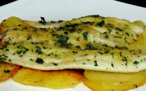 Delicioso lenguado al horno con patatas doradas y hierbas frescas.