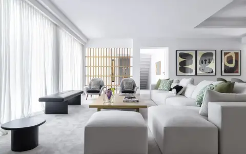 Elegante salón moderno. Sofá blanco modular, butacas grises y mesa de centro de madera. Combinar color gris en salón con toques verdes y arte abstracto.