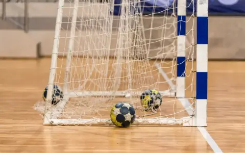 Piłki do piłki ręcznej leżą przy bramce. Poznaj zasady gry w piłkę ręczną i poczuj emocje sportowej rywalizacji!
