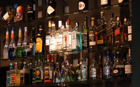 Różne rodzaje martini, szampanów i innych alkoholi na półkach baru.
