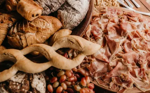 Un assortiment de pains artisanaux, de jambon cru et de raisins, parfait pour un pain sandwich italien gourmand.