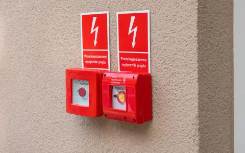 Dwa czerwone przyciski awaryjne z tabliczkami "Przeciwpożarowy wyłącznik prądu". Przepisy bezpieczeństwa wymagają ich stosowania.