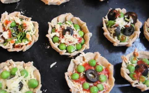 Mini pizze z groszkiem, oliwkami i serem, idealne na podwieczorek.