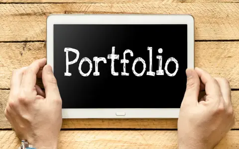 Ręce trzymają tablet z napisem "Portfolio". Idealny do prezentacji prac podczas studiów.