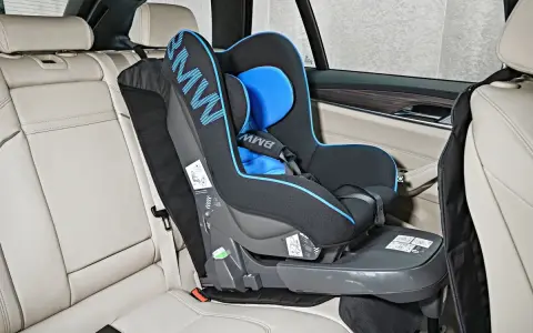 Fotelik dziecięcy BMW z systemem pasy isofix zamontowany na jasnej, skórzanej kanapie samochodowej.