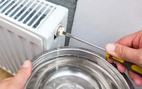 Si sta svuotando un termosifone per capire come è fatto all'interno. L'acqua esce da una valvola e cade in una bacinella.