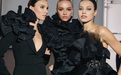Tres modelos lucen peinados recogidos elegantes, perfectos para una fiesta, con vestidos negros voluminosos y detalles de volantes.