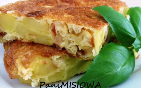 Pyszna tortilla de patatas, ze złotobrązową skórką i soczystym wnętrzem, ozdobiona świeżymi liśćmi bazylii.