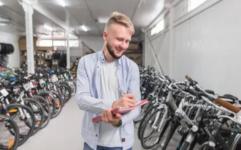 Uśmiechnięty sprzedawca notuje w zeszycie, otoczony rzędami rowerów amerykańskich marek.