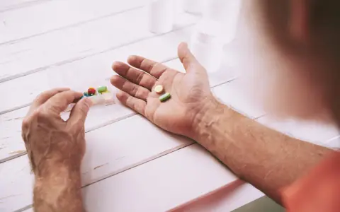 Mano che prende pillole da un portapillole. Speranza di guarigione con pembrolizumab.