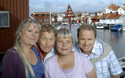 Anki Larsson och hennes vänner ler mot kameran i en charmig svensk kustby.