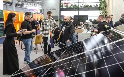 Ludzie zwiedzają targi energii odnawialnej, oglądając panele słoneczne i stoiska firm.