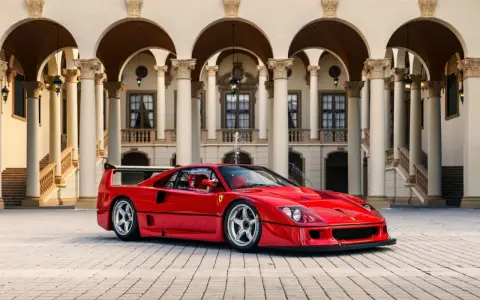 Ein roter Ferrari F40 steht vor einer prächtigen Villa mit Säulengängen.