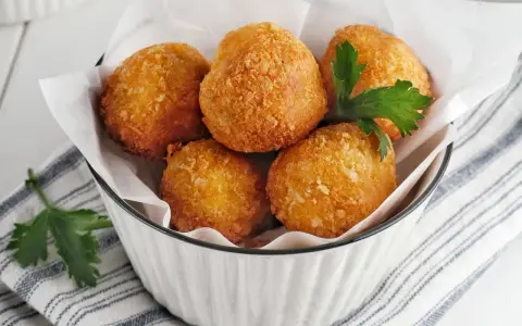 Knusprige Bitterballen, perfekt für ein leckeres Bitterballen Rezept. Serviert in einer Schüssel mit Petersilie.
