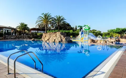 Basen w Estival Eldorado Resort z palmami i zjeżdżalniami wodnymi. Idealne miejsce na letni relaks.