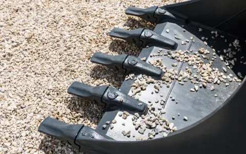 Dientes de excavadora sobre grava, una forma de como compactar tierra sin rodillo.