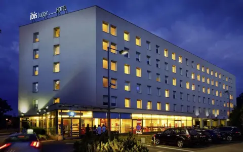 Ibis Budget Warszawa Centrum nocą. Hotel z podświetlanym logo, oknami i parkingiem.