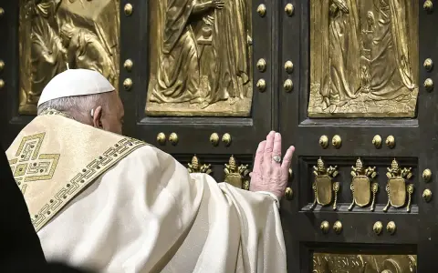 Papst Franziskus berührt die heilige Pforte des Petersdoms. Die bronzene Tür ist mit Reliefs verziert, die biblische Szenen darstellen.