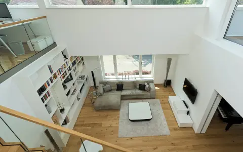 Ein offener Wohnbereich mit viel Licht und Raum. Die moderne luftraum architektur mit großen Fenstern und einer offenen Treppe schafft ein Gefühl von Weite.